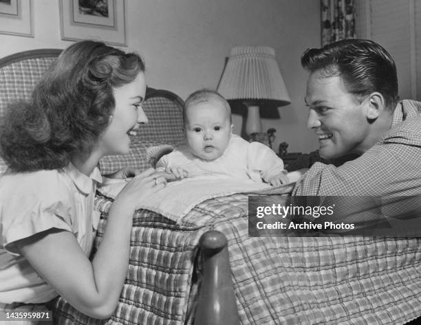 Shirley Temple and John Agar smile at their baby daughter baby Linda Susan Agar aged 3 months, United States, circa April 1948.