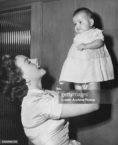 Jeanne Crain holds up her baby daughter Jeanine Brinkmna, United States, circa May 1952.