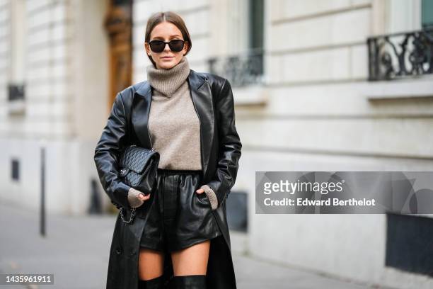 Diane Batoukina wears black leather thigh high pointed boots from Mango, a gray wool turtleneck sweater from Massimo Dutti, a long black leather...