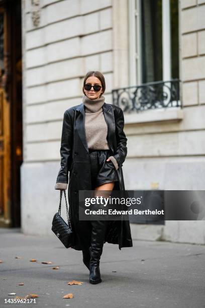 Diane Batoukina wears black leather thigh high pointed boots from Mango, a gray wool turtleneck sweater from Massimo Dutti, a long black leather...