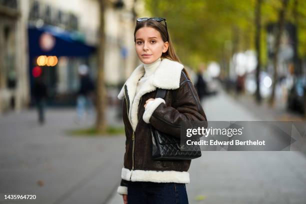 Diane Batoukina wears a brown leather aviator jacket from Massimo Dutti with white sheep wool inner lining, a white wool fringed oversized scarf from...