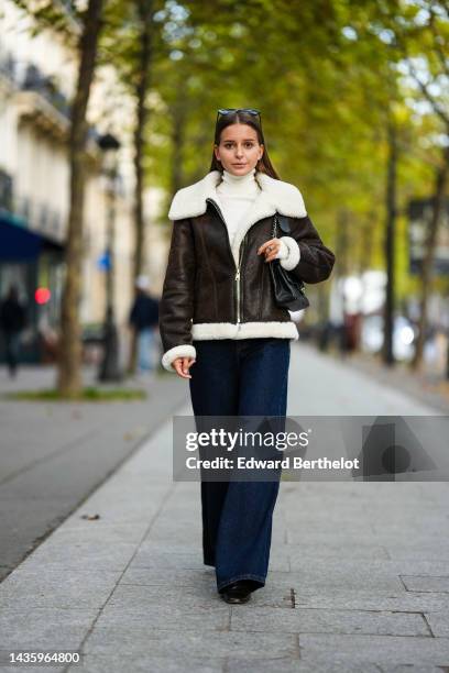 Diane Batoukina wears a brown leather aviator jacket from Massimo Dutti with white sheep wool inner lining, blue wide-leg jeans from Zara, a white...