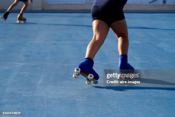 thick-legged girl dressed in black shorts riding on four-wheeled skates with protector training on the rink with her teammates - gelatinous stock pictures, royalty-free photos & images