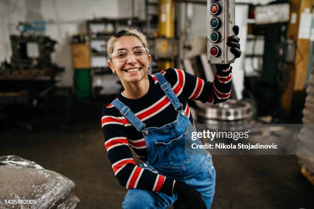 a woman uses a remote control to start a machine in a factory - washinton dc premiere of national geographics chain of command stockfoto's en -beelden