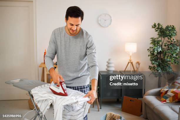 young handsome man ironing laundry at home - ironing board imagens e fotografias de stock