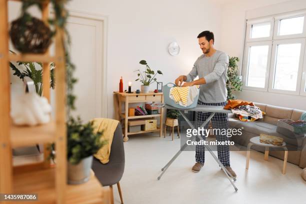 young handsome man doing chores at home - ironing board imagens e fotografias de stock