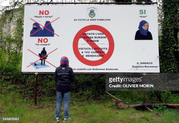 Young boy looks at a board on April 30, 2012 in Varallo, mentionning that the Burqa, Niqab and Burqini are not allowed in this city since January...