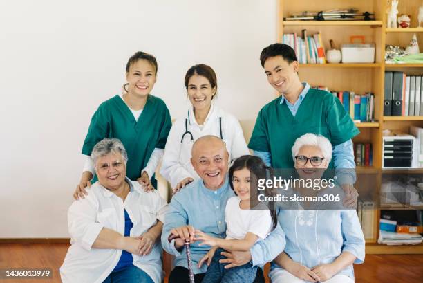 positive emotion facial expression group of aging people  and doctors and therapist and baby girl multi generation at health care center - medium group of people stock pictures, royalty-free photos & images