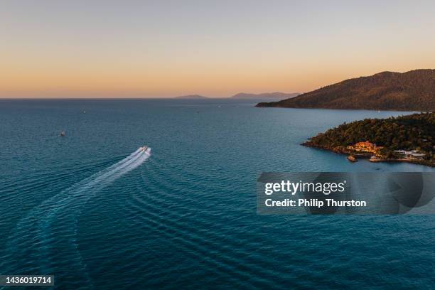 vue aérienne d’un vaste paysage océanique avec un bateau à moteur partant vers le coucher du soleil - voilier à moteur photos et images de collection