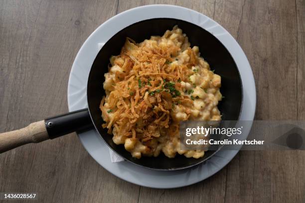 typical alpine dish with cheese pasta and onions served in a pan | tyrol, austria - alphütte stock-fotos und bilder