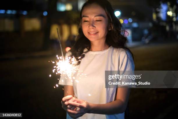 asian woman wishing while holding sparkler fireworks - chinese festival stock pictures, royalty-free photos & images