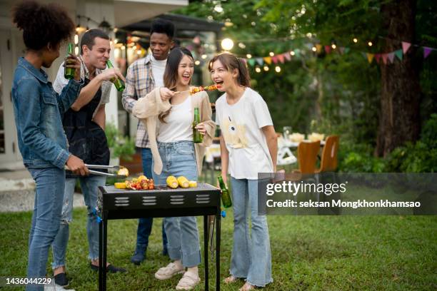 group of youngsters in backyard having fun at barbecue party. - backyard picnic stockfoto's en -beelden