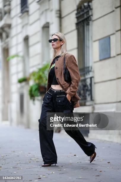 Natalia Verza wears black sunglasses from Miu Miu, silver earrings, a pearls necklace, a black with yellow and green painted pattern cropped t-shirt,...