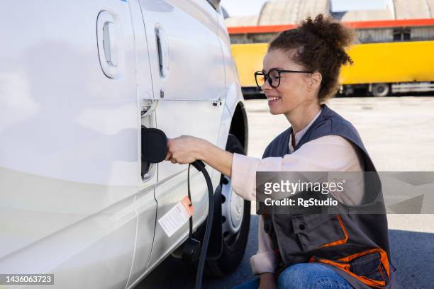 portrait of a female worker charging electric van - vilt stock pictures, royalty-free photos & images