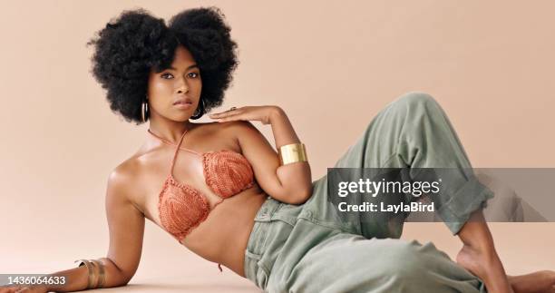 mujer negra, moda y cabello con bikini, jeans y joyas contra el fondo del estudio. modelo, segura y tumbada en el suelo con cosméticos, belleza y maquillaje retrato sobre fondo rosa en londres - pantalón mujer fotografías e imágenes de stock