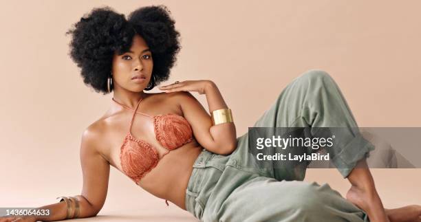 black woman, fashion and hair with bikini, jeans and jewelry against studio backdrop. model, confident and lay on floor in cosmetics, beauty and makeup portrait against pink background in london - pink trousers 個照片及圖片檔