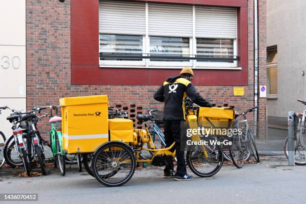 deutsche post letter carrier delivering mail with an electric bike - sending stock pictures, royalty-free photos & images