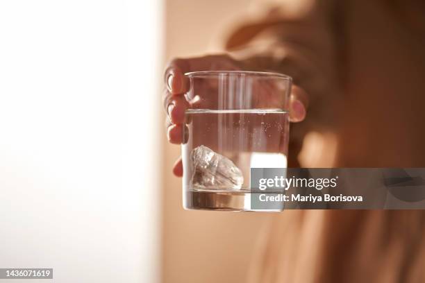 the girl's hands are a glass of water charged with a rock crystal stone. - crystal glasses stockfoto's en -beelden