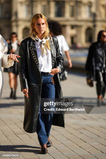 Blanca Miro wears a beige and brown silk print pattern scarf from Louis Vuitton, a white shirt, a black shiny leather nailed / studded collar long...