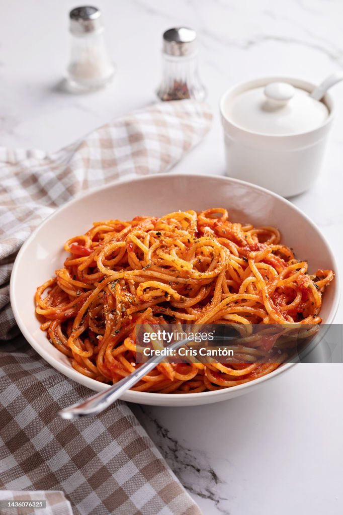 Spaghetti with tomato sauce on white background.