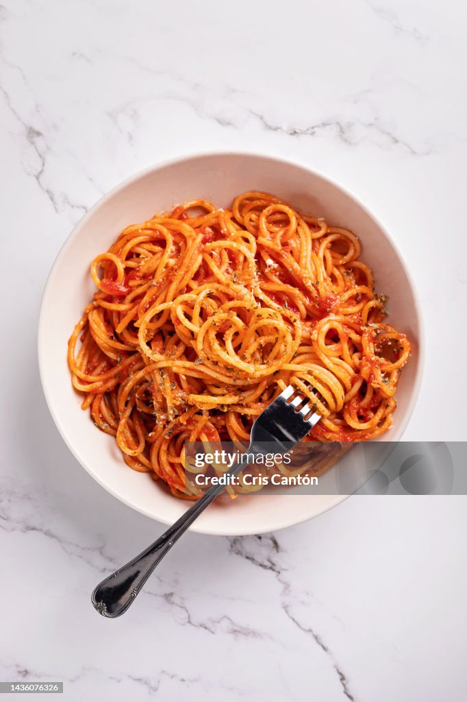 Spaghetti with tomato sauce on white background.