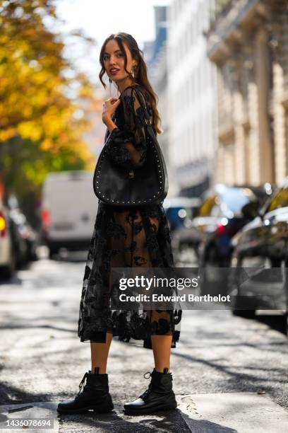 Guest wears a black tulle with embroidered fluffy leopard print pattern long sleeves / long pleated dress, a black velvet body, a black shiny leather...