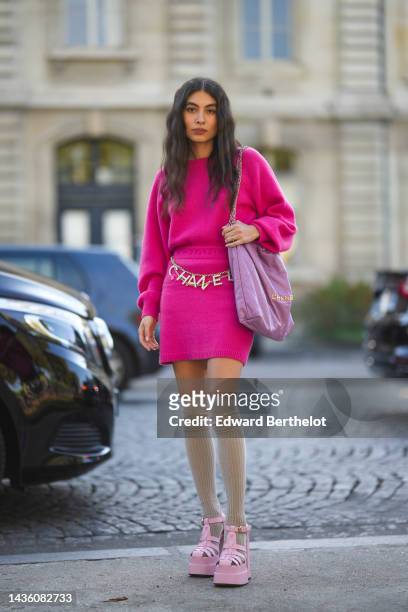 Guest wears a neon pink wool pullover from Chanel, a matching pink neon wool short skirt from Chanel, a purple shiny leather Chanel 22 shoulder bag...
