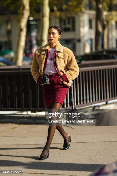 Guest wears a white cut-out print pattern t-shirt, a red tweed buttoned jacket from Chanel, a brown fluffy coat, a red tweed matching short skirt...