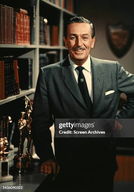 American animator, film producer and entrepreneur Walt Disney poses by Academy Award Oscar Statue in his office circa 1960. .