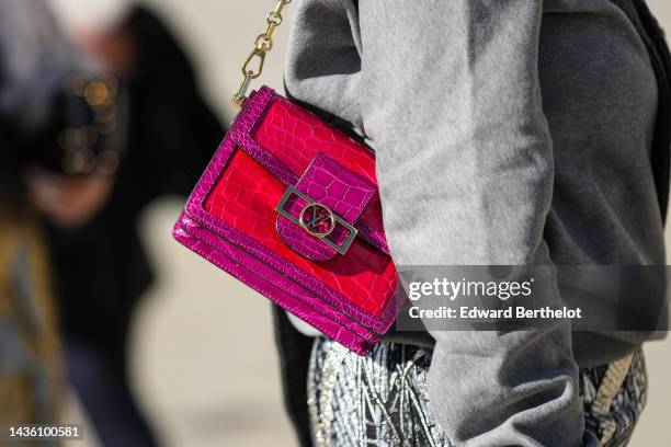 Guest wears a gray with black inscriptions print pattern sweater, a neon pink and red shiny leather crocodile print pattern shoulder bag from Louis...