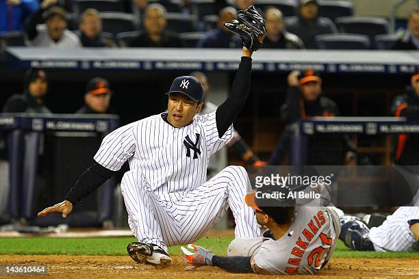 Hiroki Kuroda of the New York Yankees tags out Nick Markakis of the Baltimore Orioles who tried to steal home off of a wild pitch as Russell Martin...