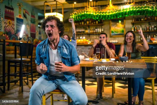 young man watching a sports game in a bar - anticipation excited stock pictures, royalty-free photos & images