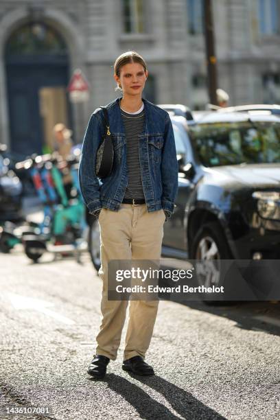 Guest wears a black and white striped print pattern wool pullover, a blue denim jacket from Levis, a black and beige logo print pattern fabric /...