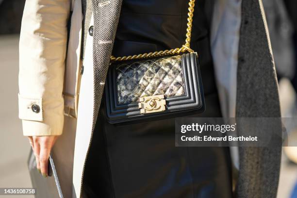 Guest wears a black shiny varnished and matte bi material leather knees dress, a beige with gray interior coat, a black shiny leather with gold...