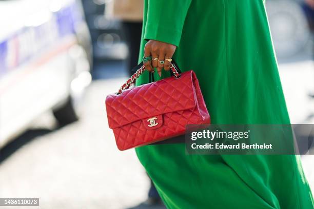 Guest wears a green oversized long silk kimono, matching green silk flowing wide legs pants, a red shiny leather Timeless handbag from Chanel, gold...