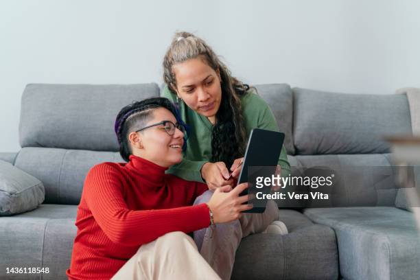latin american women connected with touchpad device buying online on white background - vita domestica fotografías e imágenes de stock