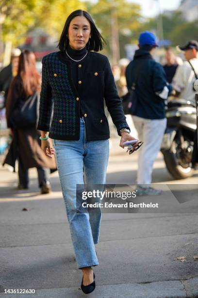 Guest wears gold earrings, a diamonds necklace, a navy blue turtleneck pullover, a half navy blue and half green and blue houndstooth print pattern...