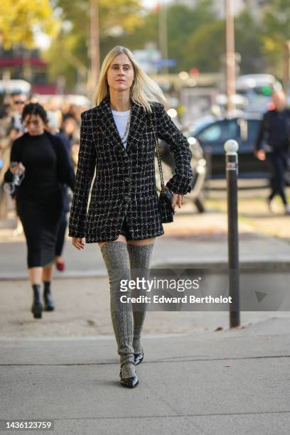 Guest wears gold earrings, a white t-shirt, a black with white checkered print pattern tweed blazer jacket from Chanel, a matching black with white...