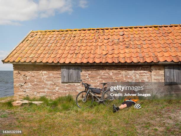 cyclist relaxing near stone house at sea - eco tourism stock pictures, royalty-free photos & images