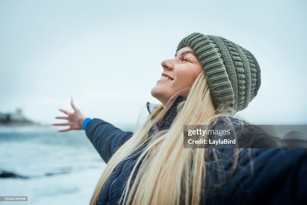 Woman, success and freedom by beach, ocean or sea in Canada with climate change goals, sustainability target and environment mindset. Happy smile, nature volunteer and marine biologist by water waves