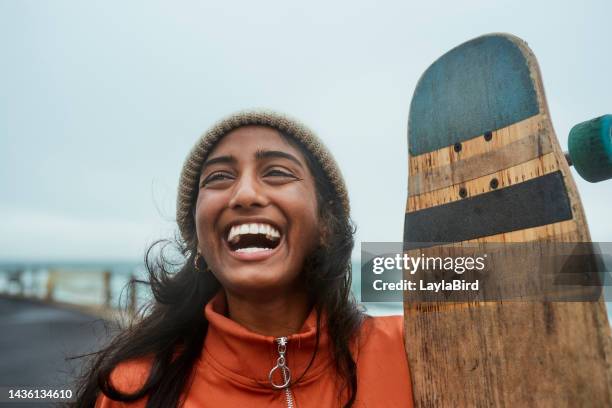 girl, happy and skateboard laughing outside for fun, relax and fitness in urban park. woman, funny and comic smile at skatepark by the ocean with cloud, sky and winter to show happiness in cape town - funny hobbies stock pictures, royalty-free photos & images