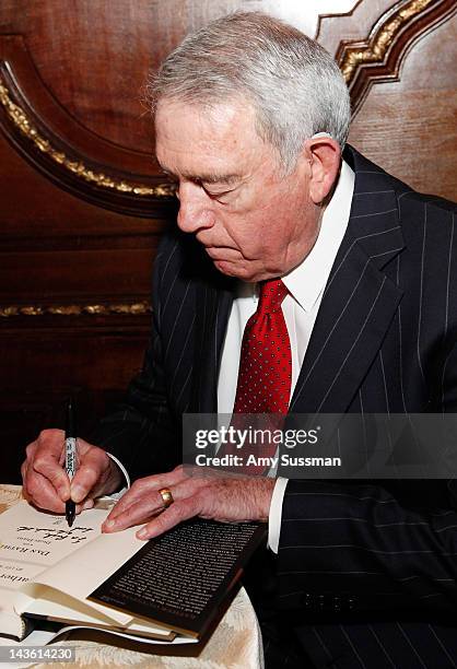 Dan Rather signs a copy of his book "Rather Outspoken: My Life In The News" at the Drawing Room at the New York Palace Hotel on April 30, 2012 in New...