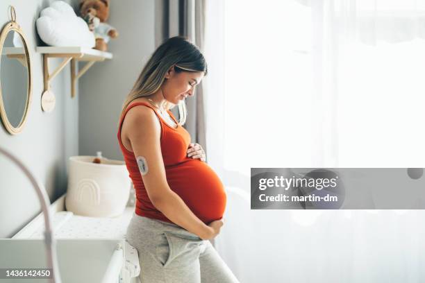 pregnant young woman with diabetes at home feeling excited about her firstborn - een dag uit het leven serie stockfoto's en -beelden