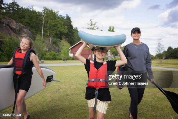 mother and children carrying paddle board - sup stock pictures, royalty-free photos & images