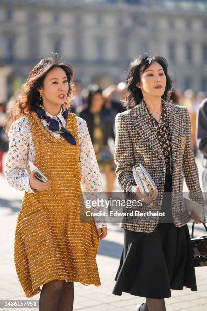 Guest wears gold pendant earrings from Louis Vuitton, a navy blue and beige print pattern silk scarf, a white with multicolored print pattern shirt...