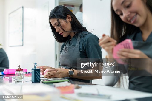 Dentistry student performs her exercises in class while working with ceramic teeth Dentistry student performs her exercises in class while working with ceramic teeth