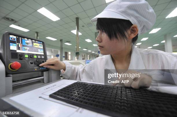 Chinese worker checks a machine to test the circuit boards at a factory in Mianyang, southwest China's Sichuan province on April 30, 2012. China's...
