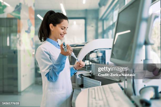 hermosa científica sonriente usando micropipeta para el análisis de pruebas - microbiologist fotografías e imágenes de stock