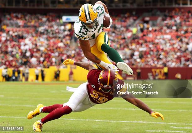 Allen Lazard of the Green Bay Packers jumps over Kendall Fuller of the Washington Commanders after a reception during the first quarter at FedExField...