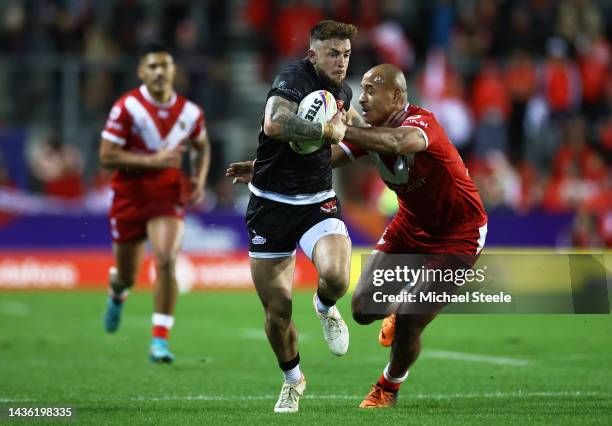 Kyle Evans of Wales breaks past the tackle of Felise Kaufusi of Tonga to score their sides first try during the Rugby League World Cup 2021 Pool D...